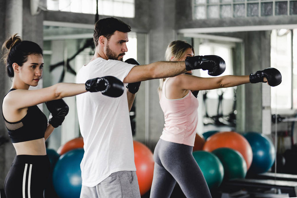 Sportieve vrouw en mannen met de rug boksen handschoenen trainen in de sportschool - Foto, afbeelding