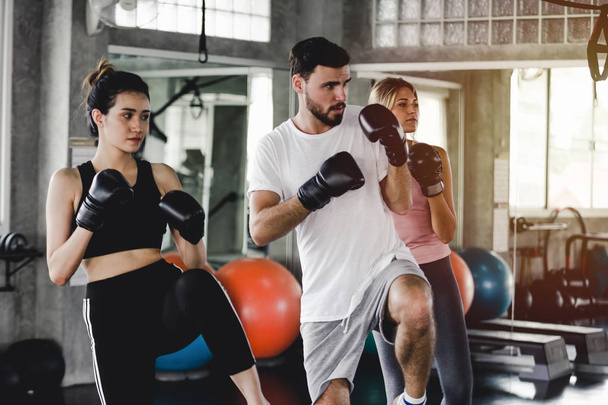 Sporty woman and men with the back boxing gloves training at the gym - Фото, изображение