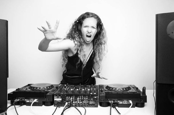 Portrait of curly hair young DJ playing music on light background - Fotó, kép