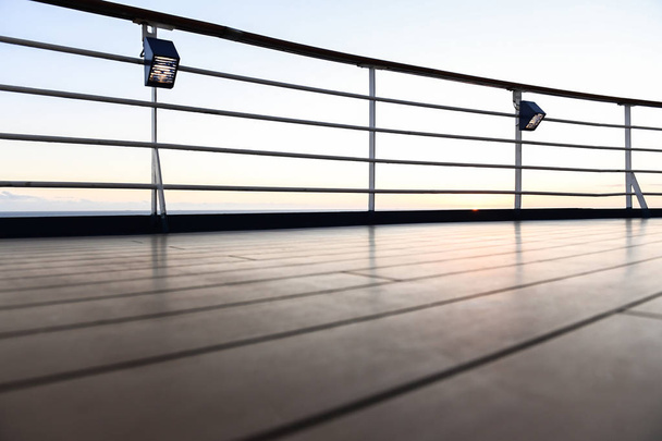 Leuning en dek vloeren van een cruise schip bij zonsondergang met de Oceaan op de achtergrond. - Foto, afbeelding