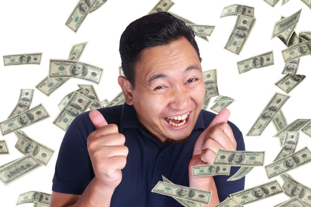 Portrait of happy successful young Asian billionaire man smiling happily under rain of money. Wealth investment economic concept - Fotoğraf, Görsel
