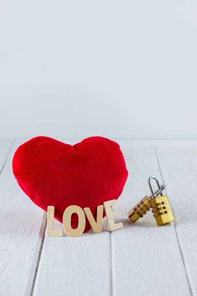 Valentinky den pozadí červené srdce tvar, dřevěných písmen slovo "Láska" a pár kombinace zlaté visací zámek na bílý dřevěný stůl a kopírování prostor pro grafiky. - Fotografie, Obrázek