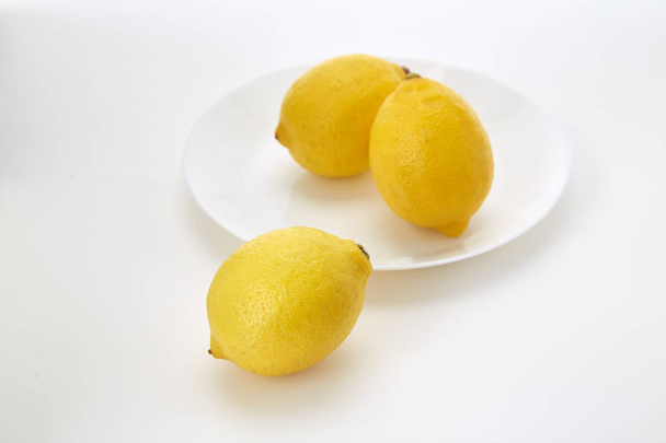 Lemons on a white plate  on a white plate with a white background and copy space - Foto, Bild