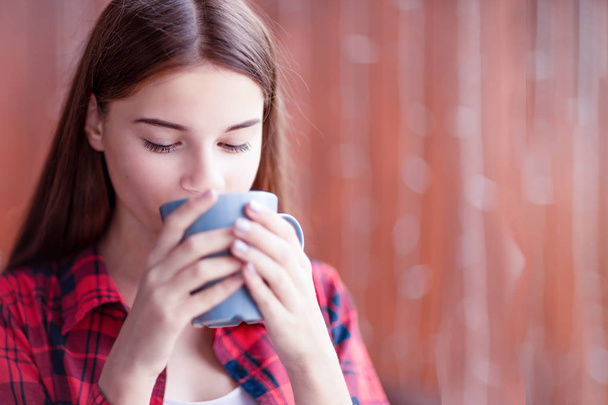 A closeup of a beautiful girl who is enjoying her tea. - Foto, Imagen