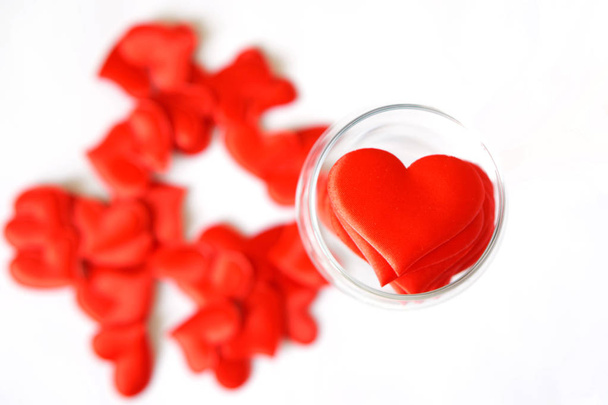 Molti cuori rossi in un bicchiere trasparente su uno sfondo bianco. Il giorno di S. Valentino. Congratulazioni per San Valentino
.                      - Foto, immagini