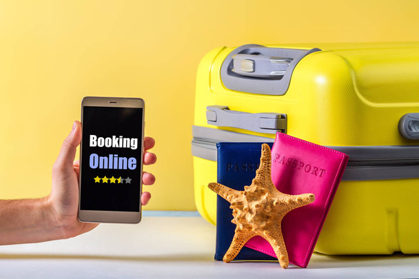 Online booking. Booking tickets and hotels on the Internet. A bright, yellow travel suitcase, passports and starfish on a yellow background. Travel concept. Leisure, vacation - Foto, Imagem