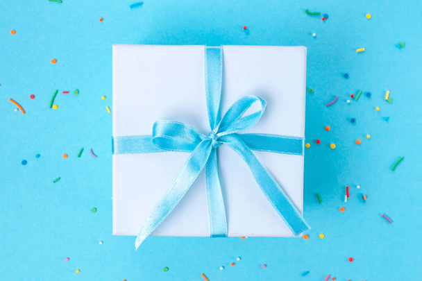 Gift, small box tied with a satin blue ribbon on a blue background. Gift concept. - Foto, Imagem