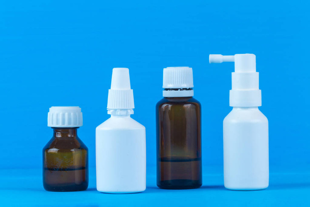 Bottles and sprays with medicine for flu and colds on a blue background. Various drugs for the sore throat and stuffy nose. Treatment of colds - 写真・画像