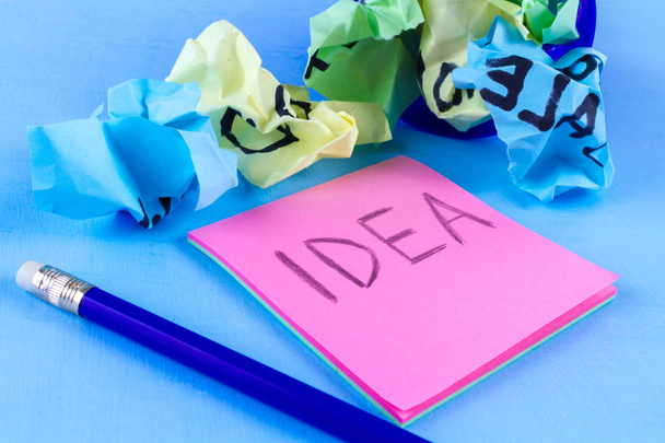 Idea concept. New idea concept. Colorful crumpled paper balls and sheets of note paper a blue background. Start up - Фото, изображение