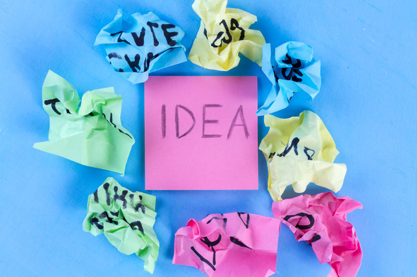 Idea concept. New idea concept. Colorful crumpled paper balls and sheets of note paper a blue background. Start up - Foto, Imagem
