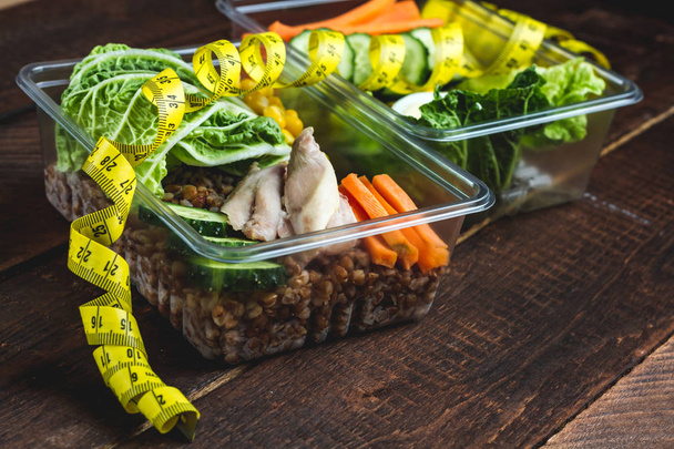 gesunde, diätetische Mahlzeit in einem Plastikbehälter und einem Maßband. Lunchbox. Ernährung und gesundes Essen. Ernährung und Gewichtsverlust Konzept. Essen Sie richtig und überwachen Sie Ihre Gesundheit. - Foto, Bild