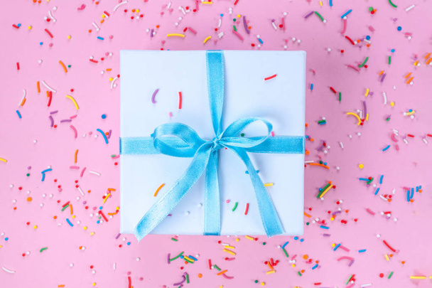 Gift, small box tied with a satin blue ribbon on a pink background. Gift concept. - Fotó, kép
