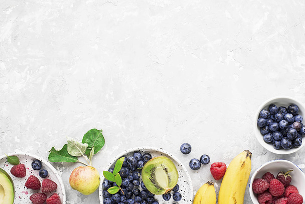 Ingredients of healthy breakfast: granola, cereal, nuts, berries, fruits, avocados, raspberries, blueberries, honey comb, pears apples kiwi banana full of fiber and vitamins Top view - Photo, Image