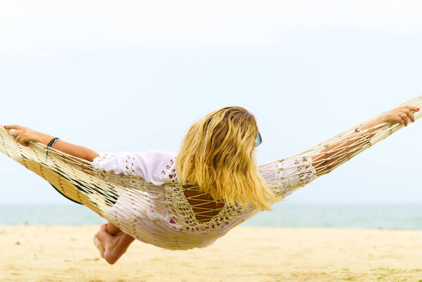 Woman sitting in hammock on the beach. Travel and vacation concept. - Foto, afbeelding