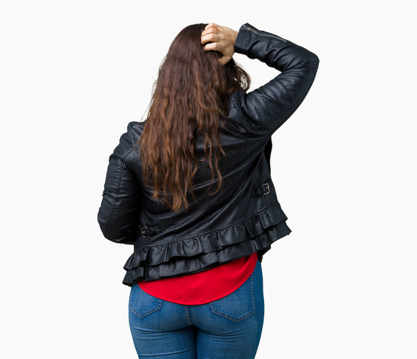 Красивая плюс размер молодая женщина в модной кожаной куртке на изолированном фоне задом наперед думает о сомнении с рукой на голове
 - Фото, изображение