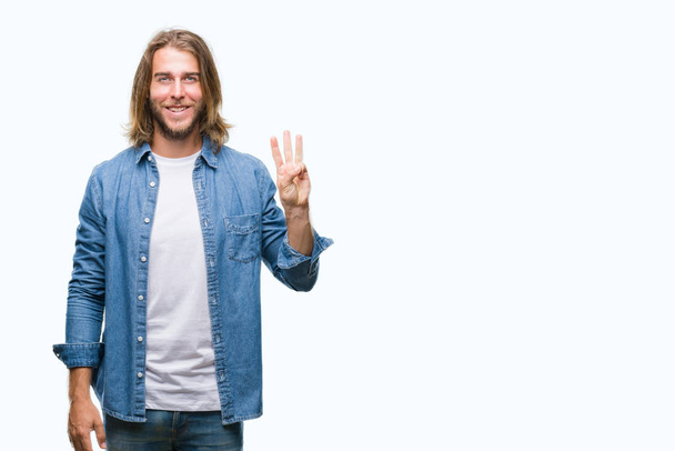 Молодой красивый мужчина с длинными волосами на изолированном фоне показывает и указывает пальцами номер три, улыбаясь уверенно и счастливо
. - Фото, изображение