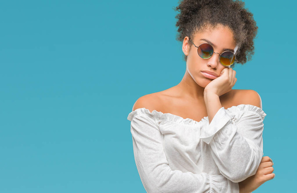Jeune femme afro-américaine portant des lunettes de soleil sur fond isolé pensant fatigué et ennuyé par des problèmes de dépression avec les bras croisés
. - Photo, image