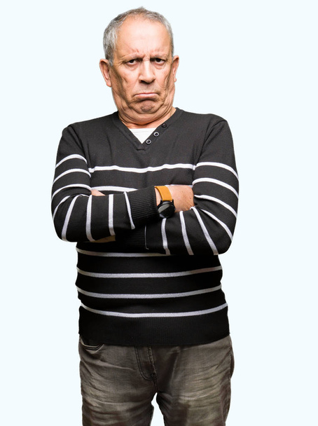 Handsome senior man wearing winter stripes sweater skeptic and nervous, disapproving expression on face with crossed arms. Negative person. - Photo, Image