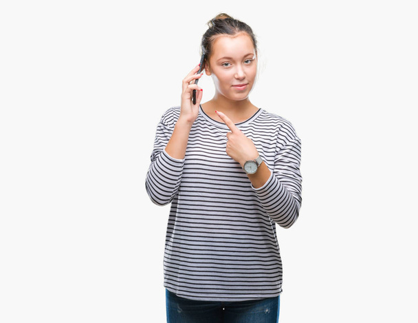 Jovem bela mulher caucasiana falando no smartphone sobre fundo isolado muito feliz apontando com mão e dedo
 - Foto, Imagem