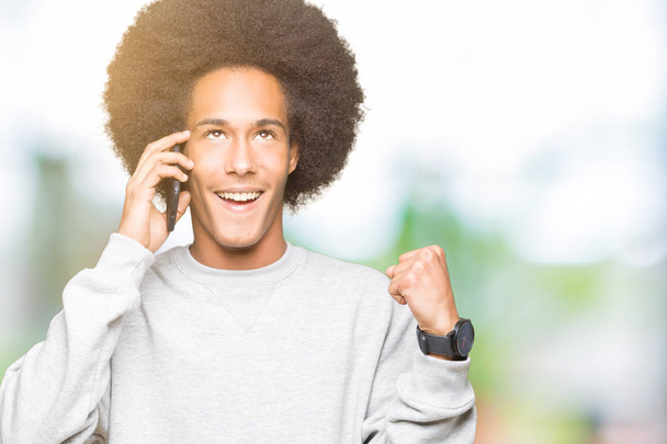 Young african american man with afro hair talking on smartphone screaming proud and celebrating victory and success very excited, cheering emotion - Fotoğraf, Görsel