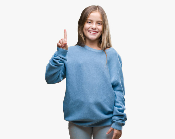 Молодая красивая девушка в зимнем свитере на изолированном фоне показывает и указывает пальцем номер один, улыбаясь уверенно и счастливо
. - Фото, изображение