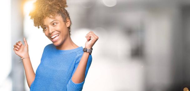 Mooie jonge african american vrouw over geïsoleerde achtergrond Dancing blij en vrolijk, glimlachend verplaatsen casual en vol vertrouwen luisteren naar muziek - Foto, afbeelding
