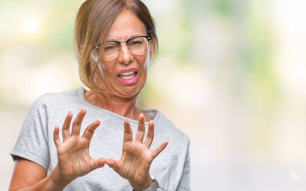 中年年配のヒスパニック系女性分離背景にメガネをかけてうんざり表現で、不快と恐ろしいので嫌悪顔をやって嫌悪反応。手で発生します。迷惑な概念. - 写真・画像