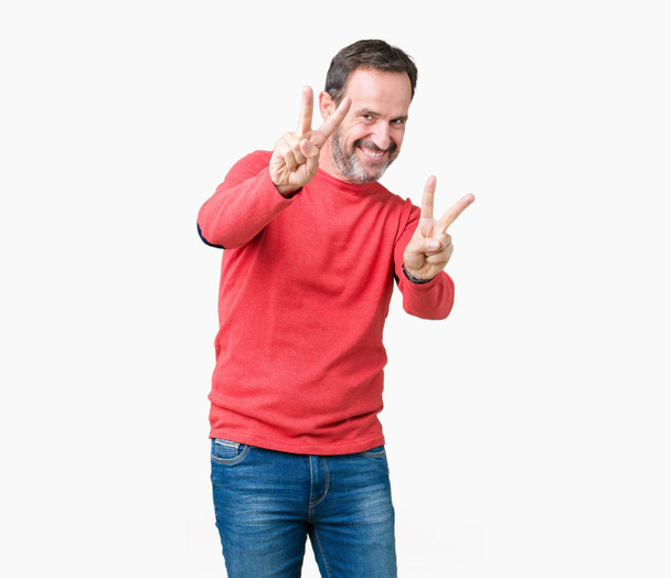 Handsome middle age hoary senior man wearing winter sweater over isolated background smiling looking to the camera showing fingers doing victory sign. Number two. - Foto, immagini