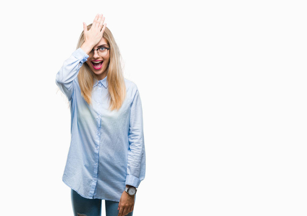 Jonge mooie blonde zakelijke vrouw dragen bril over geïsoleerde achtergrond verrast met de hand op het hoofd voor fout, niet vergeten fout. Vergat, slecht geheugen concept. - Foto, afbeelding