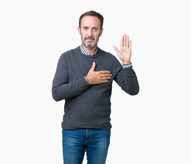 Hombre mayor de mediana edad guapo usando un suéter sobre un fondo aislado jurando con la mano en el pecho y la palma abierta, haciendo un juramento de lealtad promesa
 - Foto, Imagen