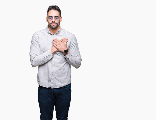 Young handsome man wearing sunglasses over isolated background smiling with hands on chest with closed eyes and grateful gesture on face. Health concept. - Φωτογραφία, εικόνα