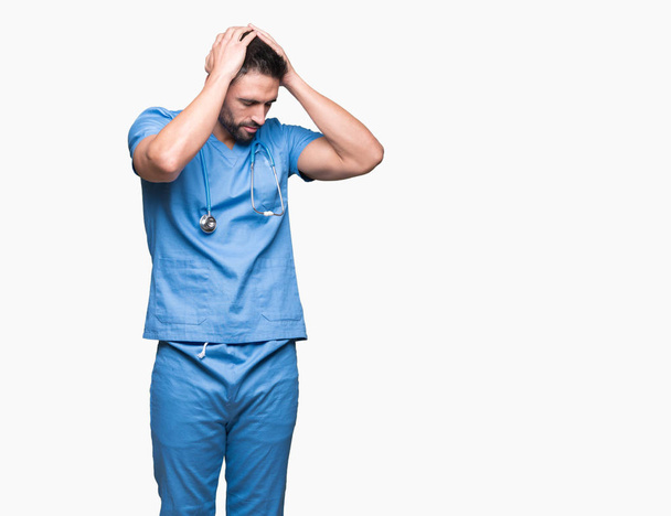 Handsome young doctor surgeon man over isolated background suffering from headache desperate and stressed because pain and migraine. Hands on head. - Fotoğraf, Görsel
