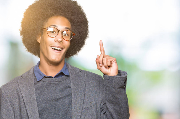 Jonge Afro-Amerikaanse zakenman met afro haar bril vinger omhoog met succesvolle idee. Verlaten en gelukkig. Nummer één. - Foto, afbeelding