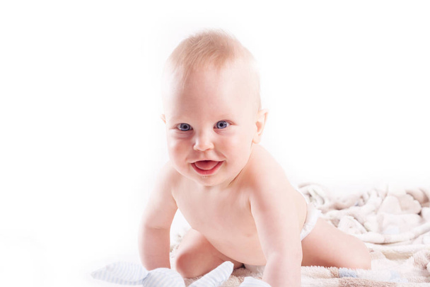 Sweet 9 monts baby boy in napkin crawling and playing with toys on a blanket - studio shot - Foto, afbeelding