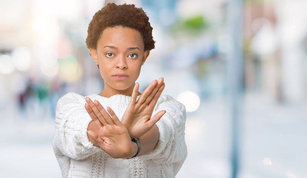 Belle jeune femme afro-américaine portant un pull sur fond isolé Expression de rejet croisant les bras et les paumes faisant signe négatif, visage en colère
 - Photo, image