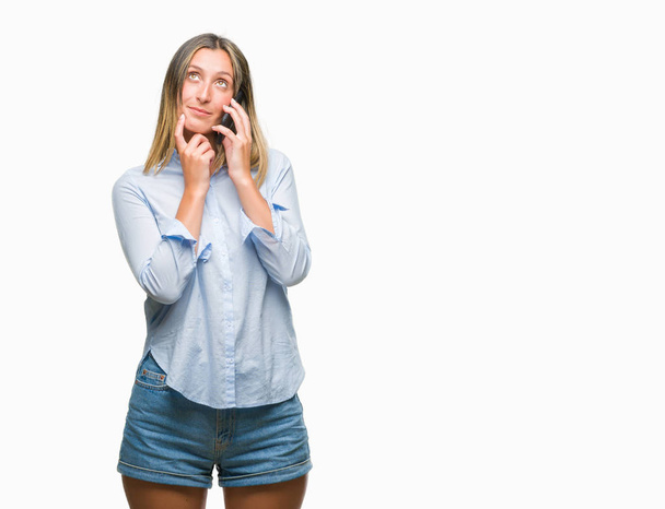 Молодая красивая женщина говорит на смартфоне на изолированном фоне серьезное лицо, думая о вопросе, очень запутанная идея
 - Фото, изображение