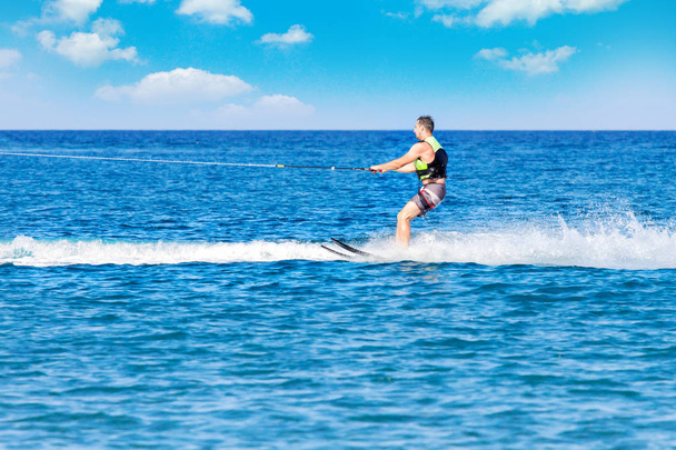 Jeune homme glisse sur le ski nautique sur les vagues sur la mer, l'océan. Mode de vie sain. Émotions humaines positives, sentiments, joie. Vacances de printemps et d'été
. - Photo, image