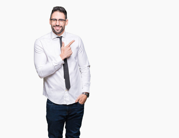 Young handsome business man wearing glasses over isolated background cheerful with a smile of face pointing with hand and finger up to the side with happy and natural expression on face - Photo, Image