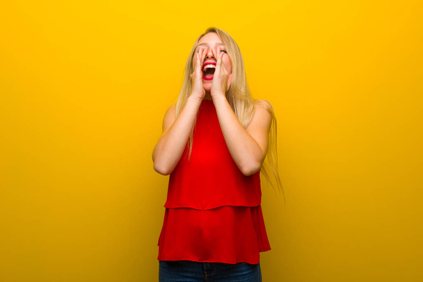 Menina com vestido vermelho sobre a parede amarela gritando e anunciando algo
 - Foto, Imagem