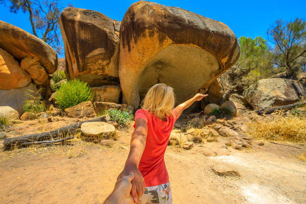 Follow me, woman holding hands at Hippos Yawn, a hippo-shaped rock near Wave Rock in Hyden, Australian outback, Western Australia. Concept of journey of tourist traveler, holding man by hand. - Photo, Image