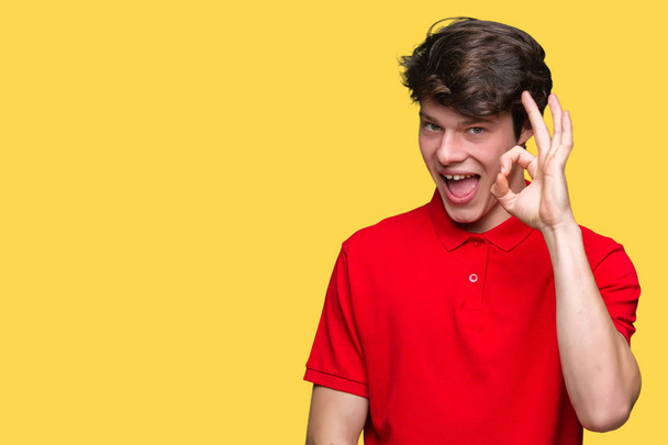 Mladý pohledný muž na sobě červené tričko přes izolované pozadí s úsměvem pozitivní jednání ok znamení rukou a prstů. Úspěšné výraz. - Fotografie, Obrázek