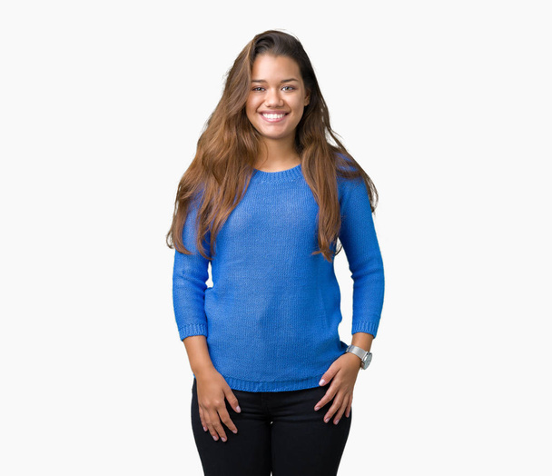 Μελαχρινή νεαρή όμορφη γυναίκα φορώντας μπλε πουλόβερ πάνω από απομονωμένες φόντο με μια ευτυχισμένη και δροσερό χαμόγελο στο πρόσωπο. Τυχερό πρόσωπο. - Φωτογραφία, εικόνα
