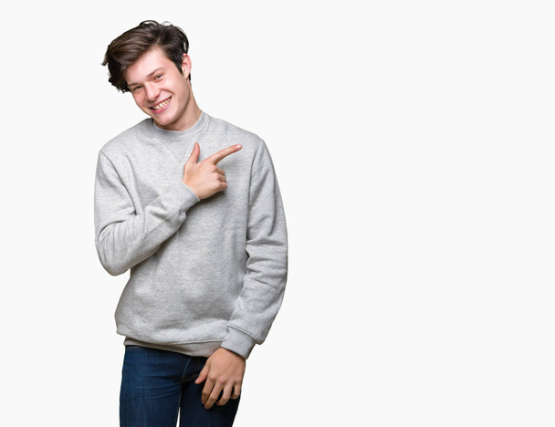 Csinos sportos fiatalember visel pulóver felett vidám mosollyal az arcát mutatva a kéz és az ujjak, akár az oldalán arcán boldog és természetes kifejezés elszigetelt háttér - Fotó, kép