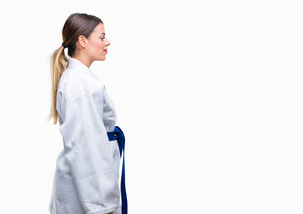Mujer hermosa joven con uniforme de kimono de karate sobre fondo aislado mirando a un lado, pose de perfil relajado con cara natural con sonrisa confiada
. - Foto, imagen