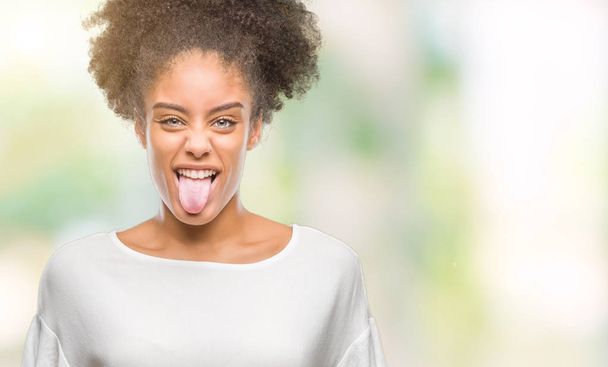 Giovane donna afro-americana su sfondo isolato attaccare lingua fuori felice con espressione divertente. Concetto di emozione
. - Foto, immagini