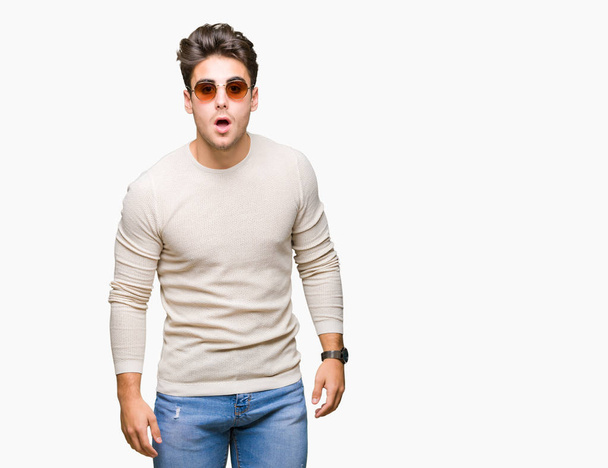 Mladý pohledný muž nosí sluneční brýle izolované pozadí strach a šokován s výrazem překvapení, strach a vzrušený obličej. - Fotografie, Obrázek