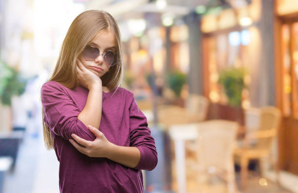 Young beautiful girl wearing sunglasses over isolated background thinking looking tired and bored with depression problems with crossed arms. - Фото, зображення