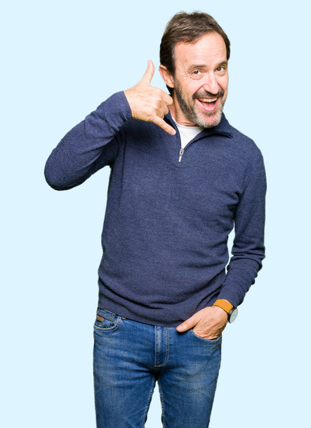 Orta yaş yakışıklı adam yapıyor gülümseyen bir kazak giyen telefon hareketi ile el ve parmak telefonda konuşuyor gibi. Kavramları iletişim. - Fotoğraf, Görsel