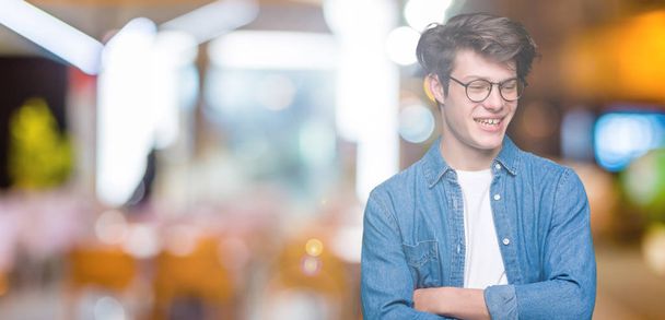 Young handsome man wearing glasses over isolated background happy face smiling with crossed arms looking at the camera. Positive person. - Foto, Bild