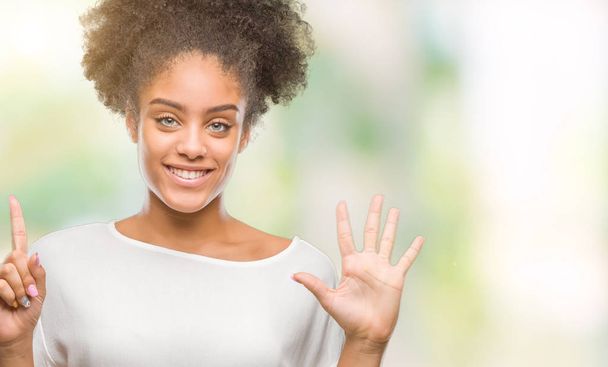Αφρο αμερικανικό γυναίκα πέρα από το απομονωμένο υπόβαθρο δείχνει και δείχνει προς τα επάνω με τα δάχτυλα αριθμός έξι ενώ χαμογελώντας αυτοπεποίθηση και χαρούμενοι. - Φωτογραφία, εικόνα